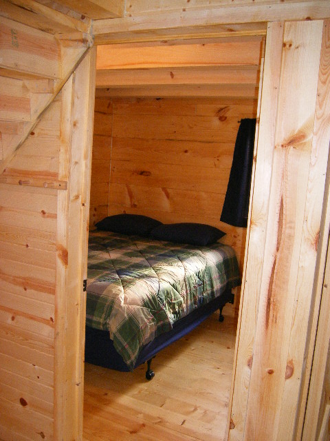 Interior of cabin looking through doorway into a bedroom with a queen sized bed.